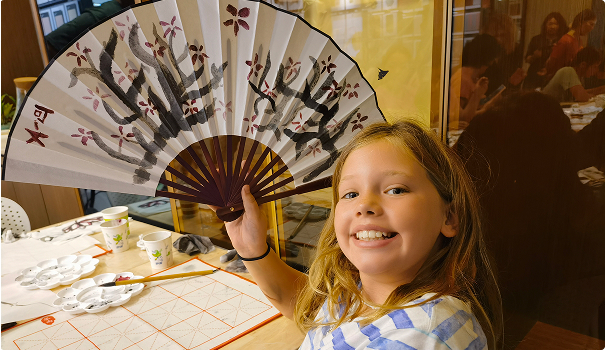 Young girl smiling holding Chinese paper fan