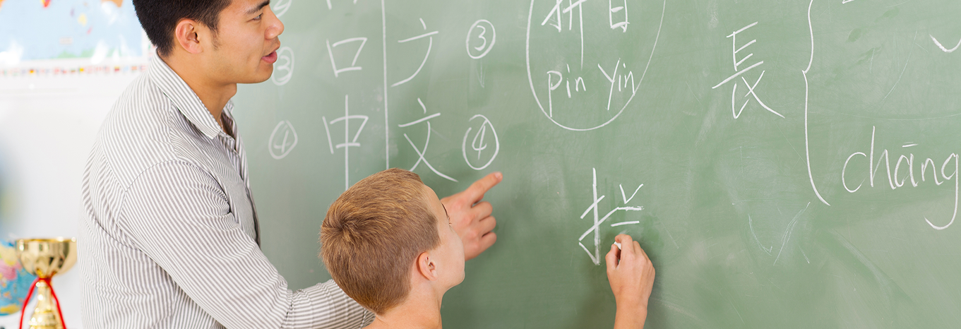Chinese teacher and young student at chalkboard