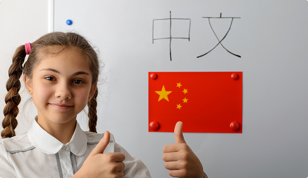 Young blonde girl giving thumbs up in front of Chinese flag