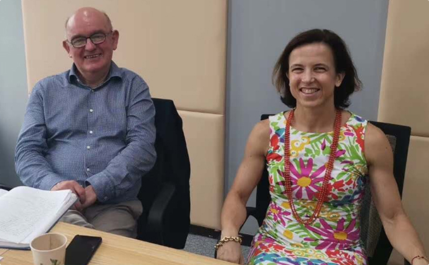Man in blue shirt and woman in floral dress smiling