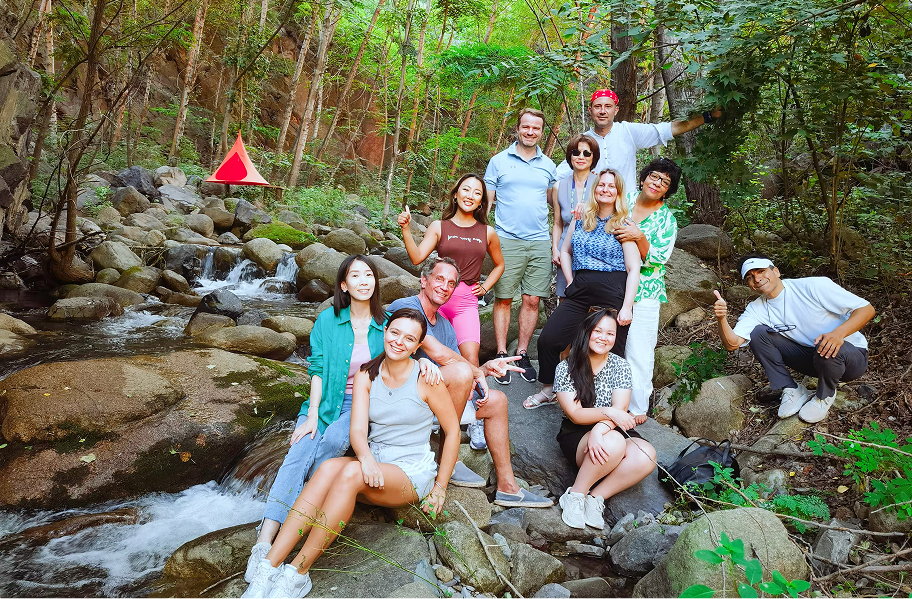 Group of people smiling and posing by a stream